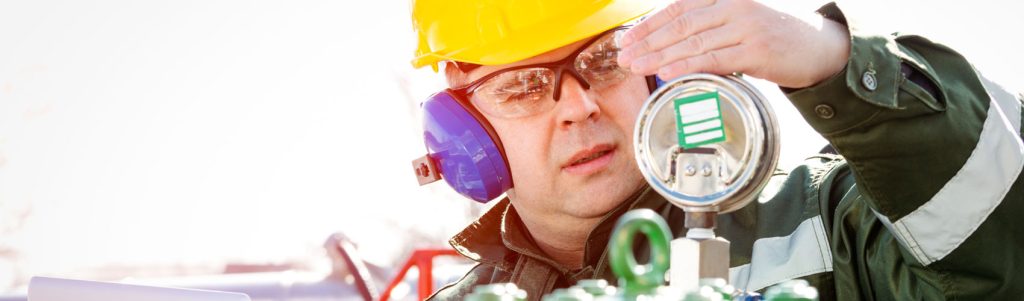 Engineer with safety gear, checking a gauge